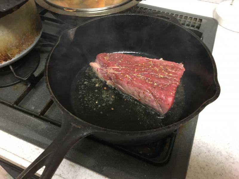 強火にして煙が出てくるまでダッチオーブンを加熱したら肉を投入。一つの面で30秒～1分くらい焼き目をつけます。
