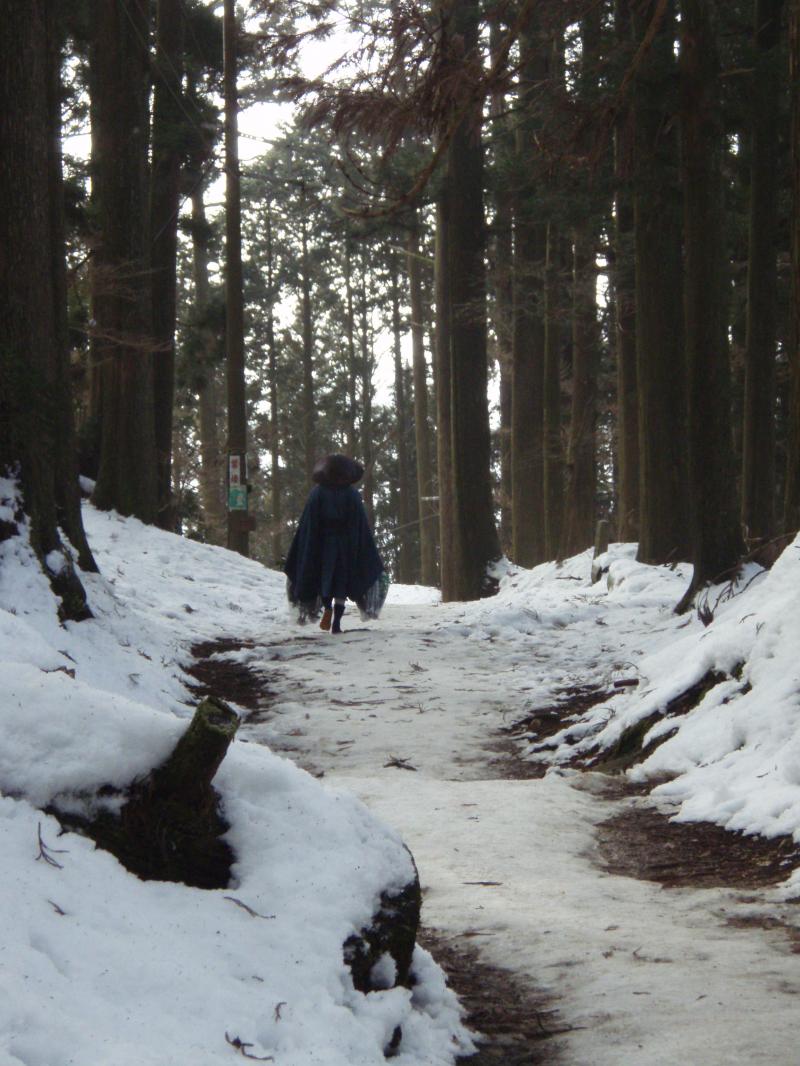 両手に荷物を持ったまま凍った雪道を歩く修行僧