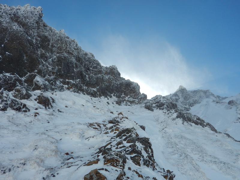 浅いルンゼ状の凍った草付きを右上する。上部岩稜へ。登りつめた岩壁基部にビレイポイントあり。